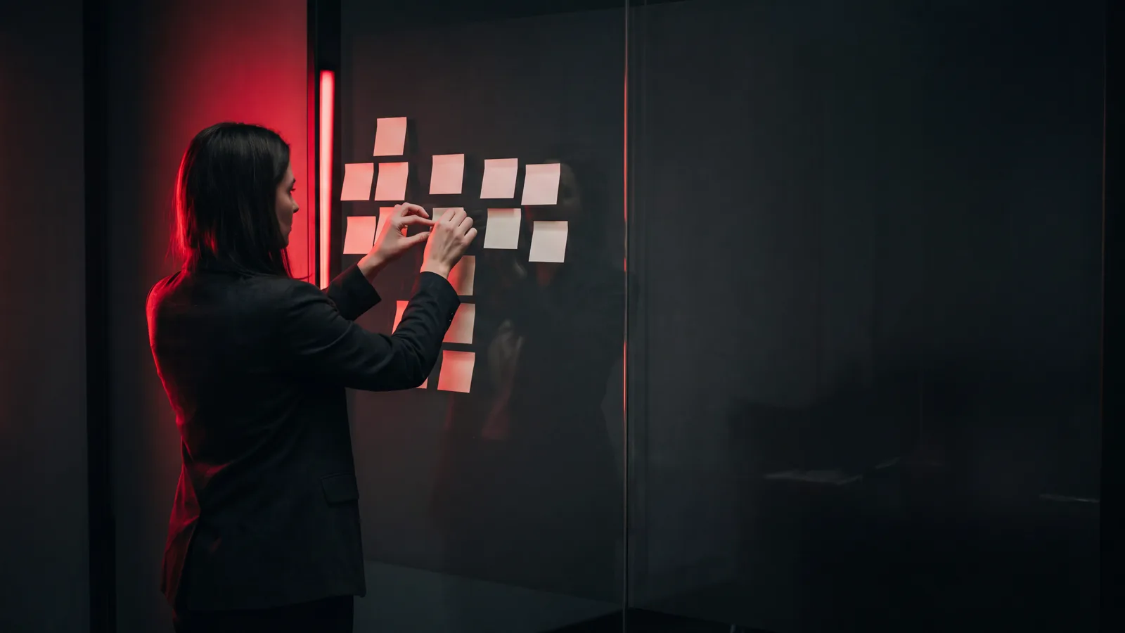A strategist arranging cards into a branching channel plan on a dark glass wall