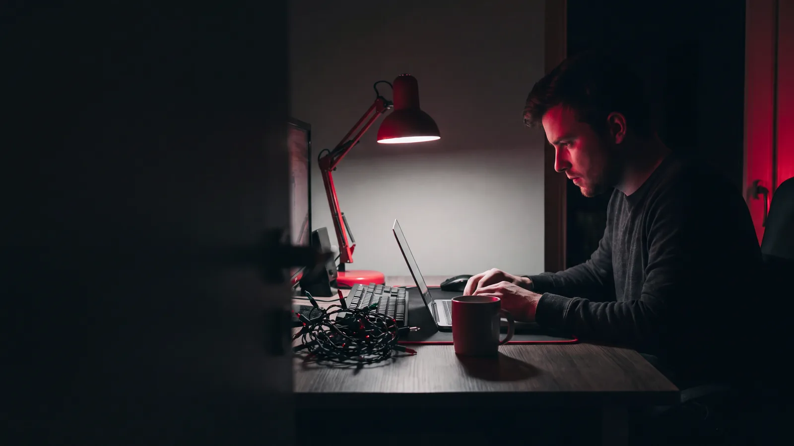 An email marketer working late, a coiled string of festive bulbs beside the keyboard