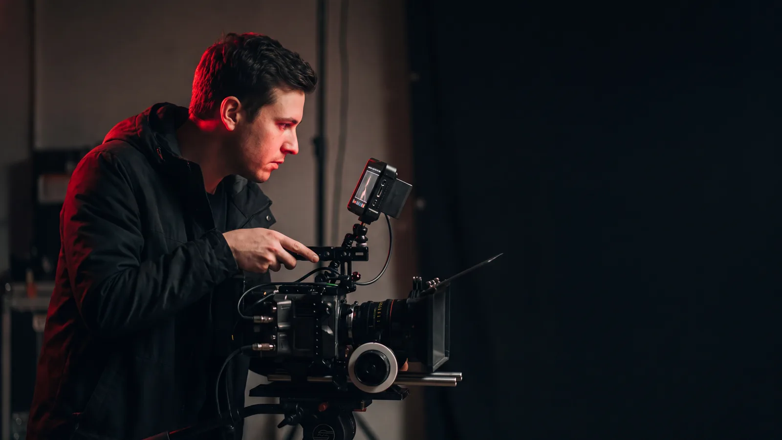 A content producer checking a cinema camera monitor on a darkened set